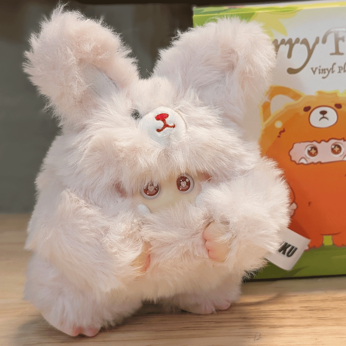 OHKU Giggle Monster Furry Forest plush figure in fluffy pink bunny costume with expressive eyes on wooden surface
