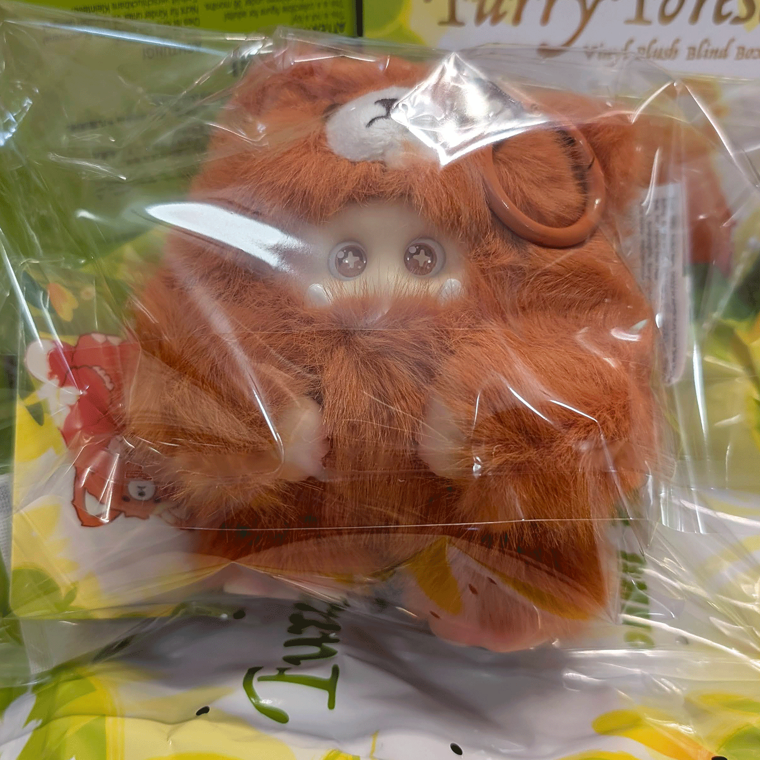 OHKU Giggle Monster plush figure in fuzzy rust-colored bear costume with shiny round eyes inside clear packaging