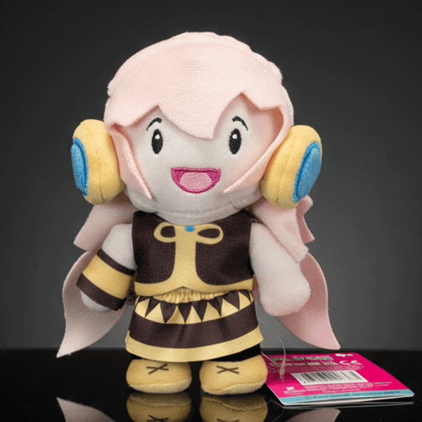 Front view of UCC 6-inch Megurine Luka plush with pink hair, yellow headphones, and detailed brown outfit standing on black surface