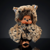 Sekiguchi 8-inch Monchhichi plush doll wearing leopard hood and cape with thumb in mouth on dark background