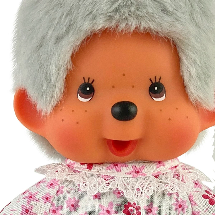 Close-up of a Monchhichi doll face with gray hair, rosy cheeks, freckles, and a floral lace collar dress.