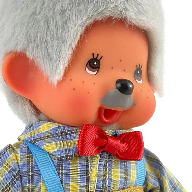 Close-up of a vintage-style doll with gray hair, red bow tie, and plaid shirt featuring suspenders