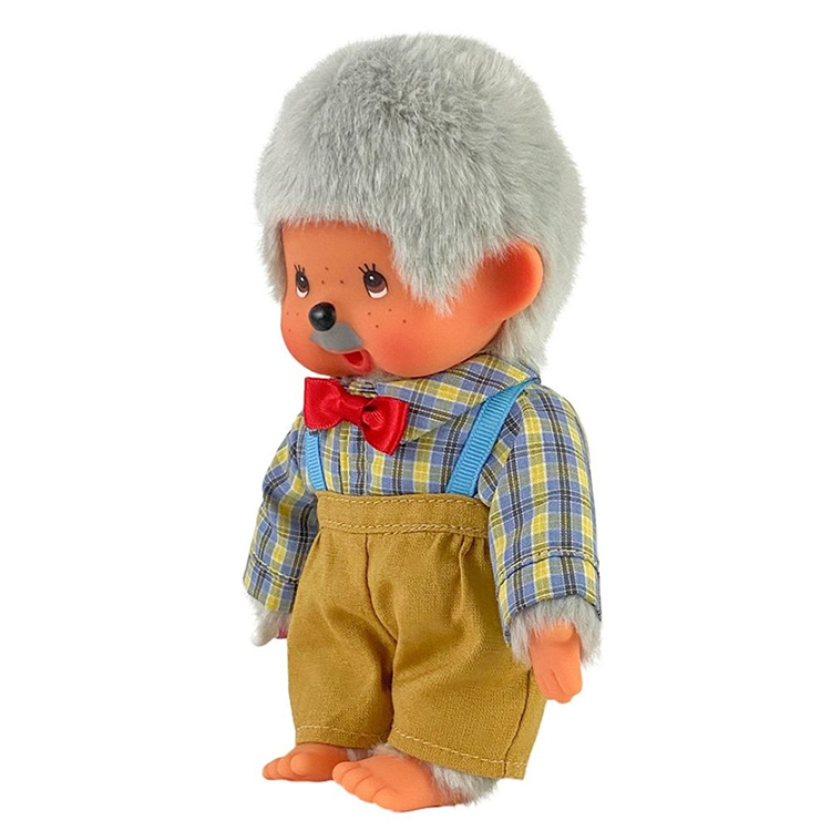 Vintage Monchhichi doll with gray hair, red bow tie, plaid shirt, and brown suspenders shorts standing on white background