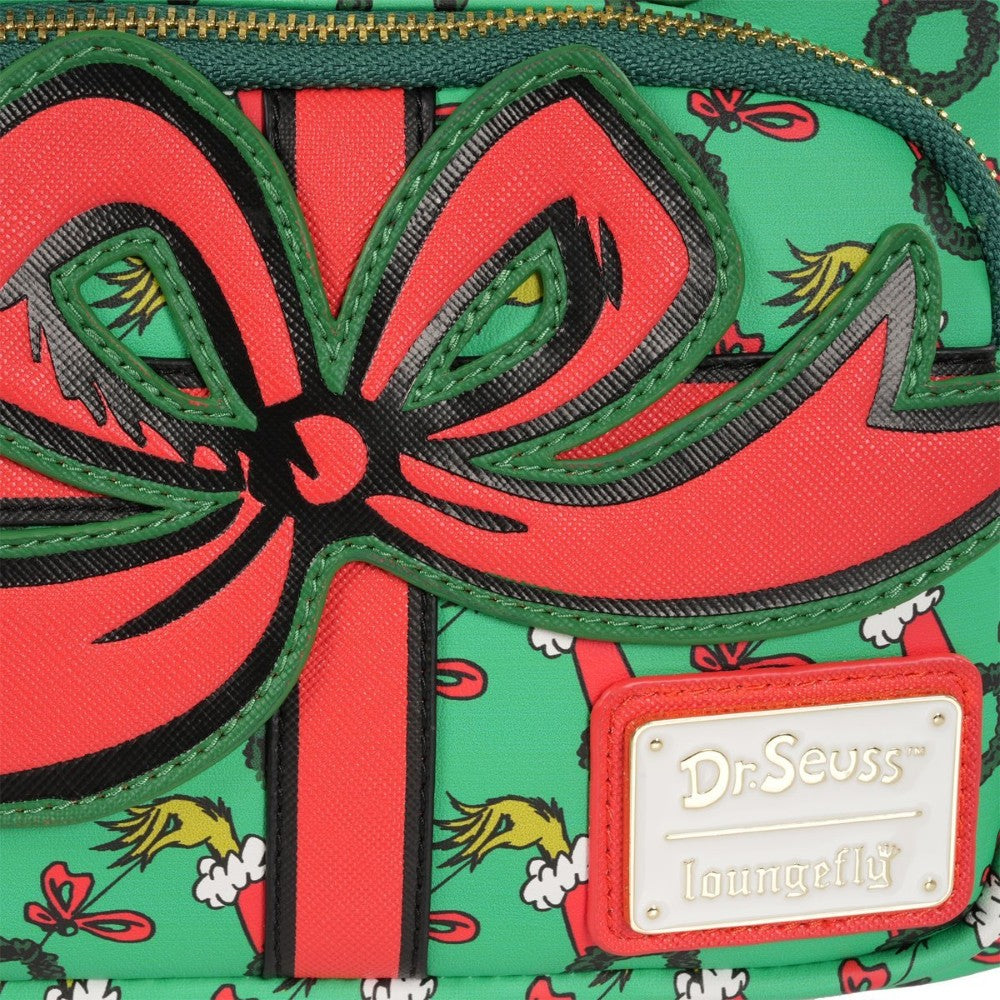 Close-up of Loungefly mini-backpack showing red bow detail and green background with Grinch motifs and Dr. Seuss logo plaque