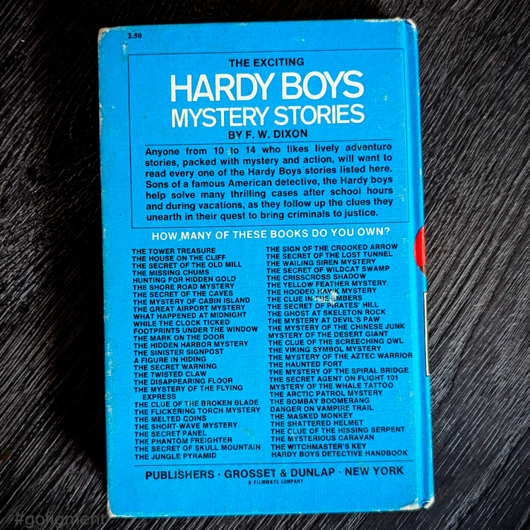 Vintage Hardy Boys mystery book back cover by Grosset & Dunlap featuring a blue bar and series titles list