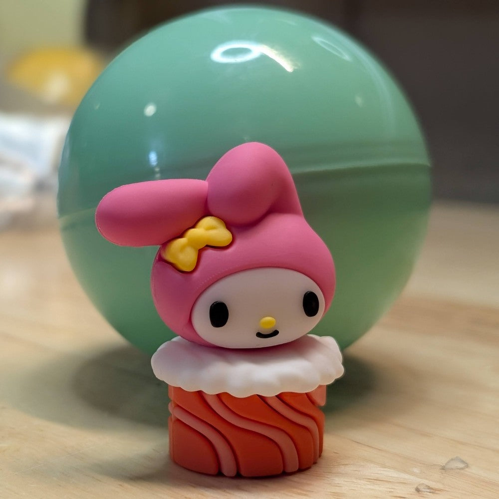 Go Figment Hello Kitty and Friends collectible capsule featuring My Melody character on sushi base with pink hood and yellow bow