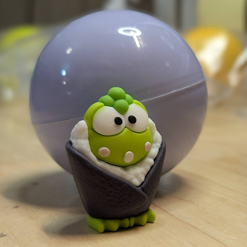 Go Figment figure featuring green character with large eyes wrapped in dark purple seaweed sushi cone with rice detail