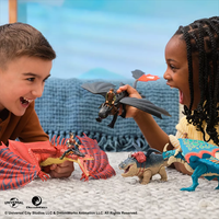 Two children playing excitedly with How to Train Your Dragon final battle figure set including dragons and Vikings