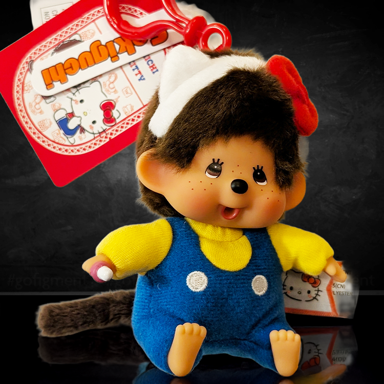 Sekiguchi Monchhichi plush bag clip dressed as Hello Kitty in blue overalls with headband and bow, 4.7 inches tall.