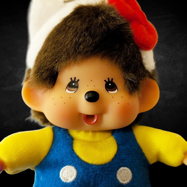 Sekiguchi Monchhichi plush bag clip dressed as Hello Kitty in overalls with red bow headband close-up