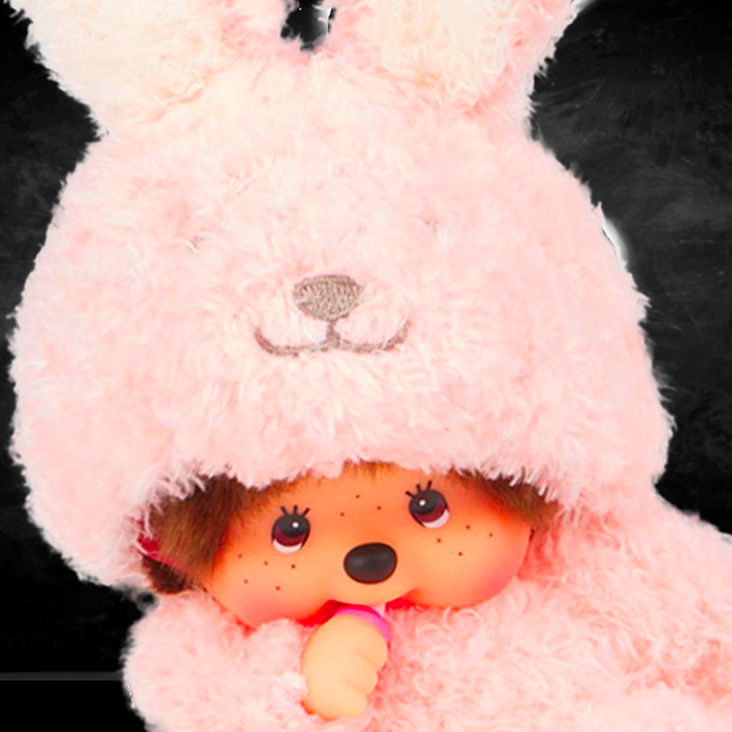 Sekiguchi Monchhichi sitting doll in soft pink fluffy bunny costume with thumb in mouth on dark background