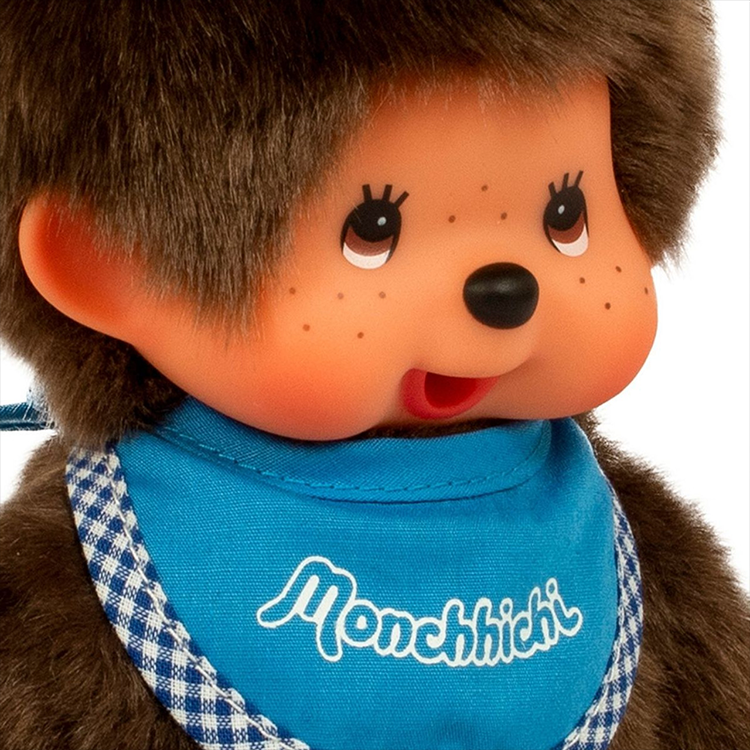 Close-up of Sekiguchi Monchhichi plush toy with soft fur and blue bib featuring classic logo.