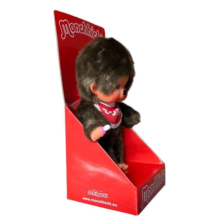 Monchhichi doll with brown fur and red bib in a red display box