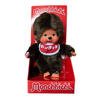 Monchhichi doll with dark brown fur, blue eyes, and red bib in red Monchhichi packaging