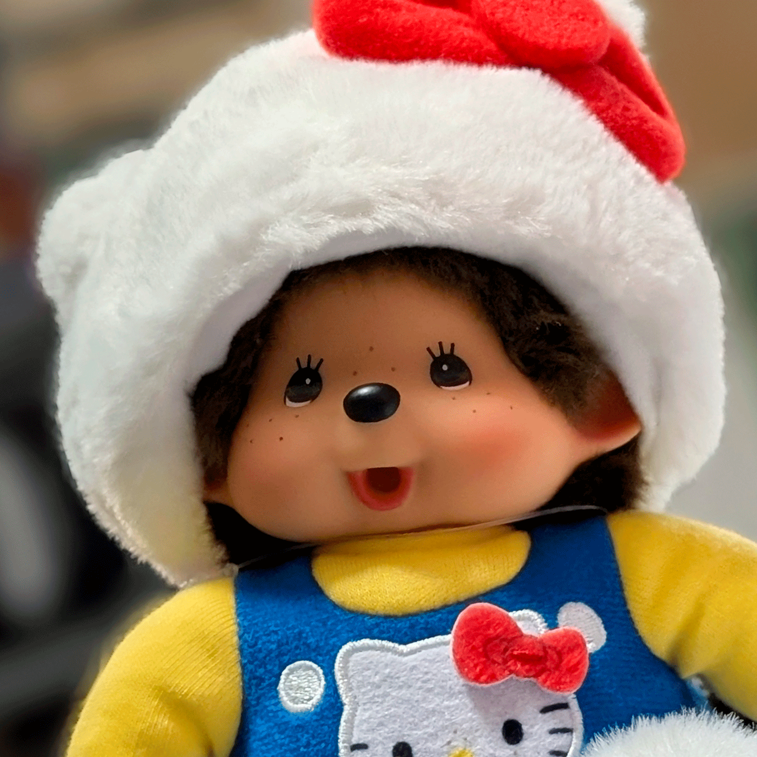 Sekiguchi Monchhichi plush doll dressed as Hello Kitty in white cat hat and blue overalls with red bow detail