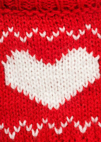 Close-up of a red knitted fabric with a large white heart and zigzag pattern