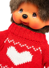 Brown haired doll with freckles wearing a red knitted sweater with a white heart pattern
