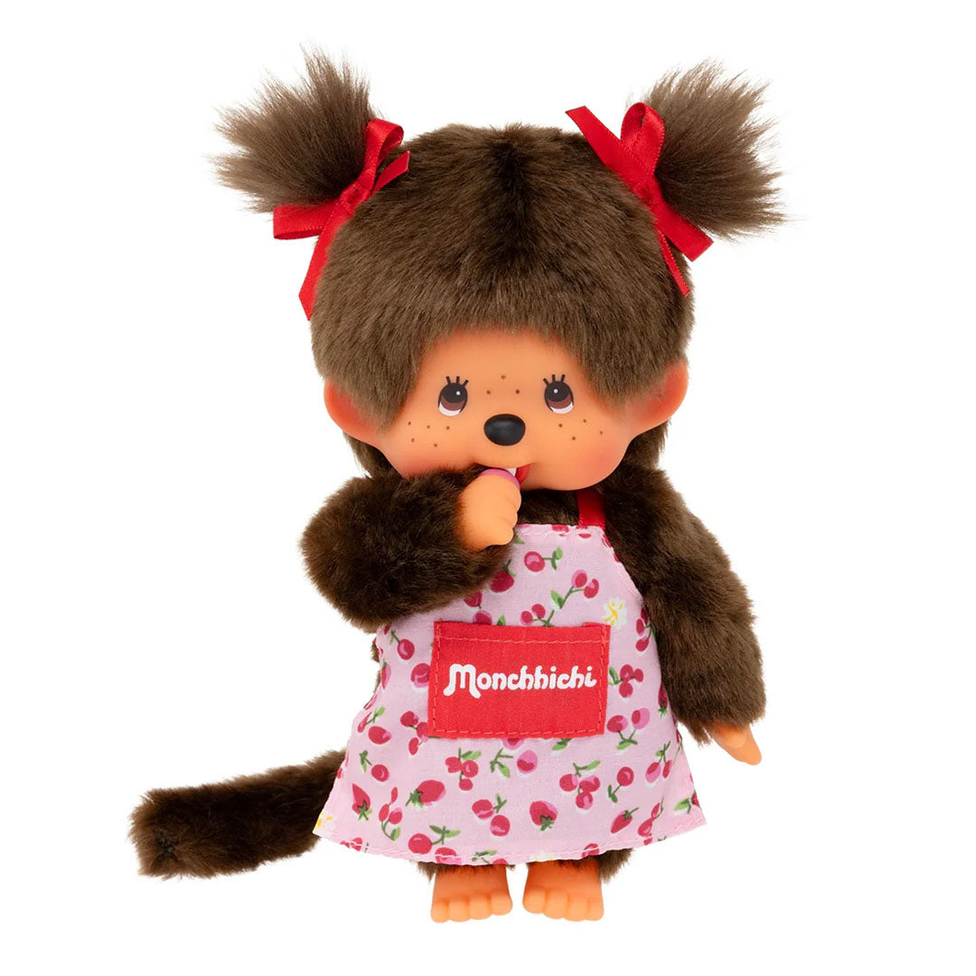 Sekiguchi Monchhichi Girl plush doll wearing pink flower apron with red bows and thumb in mouth, 8 inches tall