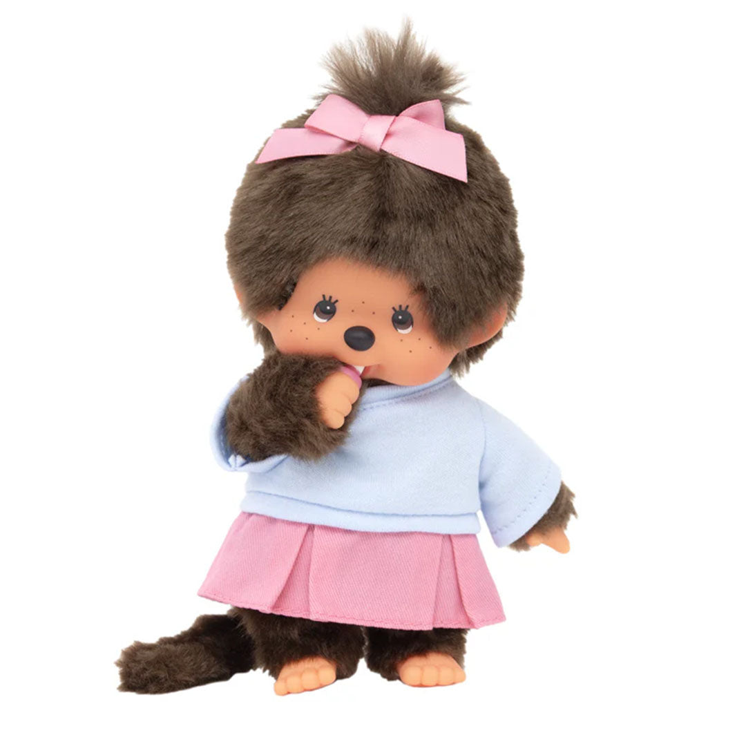 Sekiguchi Monchhichi Girl plush monkey in pink pleated skirt, light blue shirt, and thumb-sucking pose.