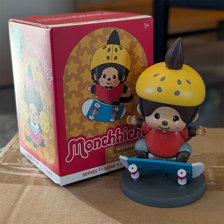 Sekiguchi Monchhichi Boy Skateboarder vinyl figure in yellow helmet and red shirt on blue skateboard with gray base.
