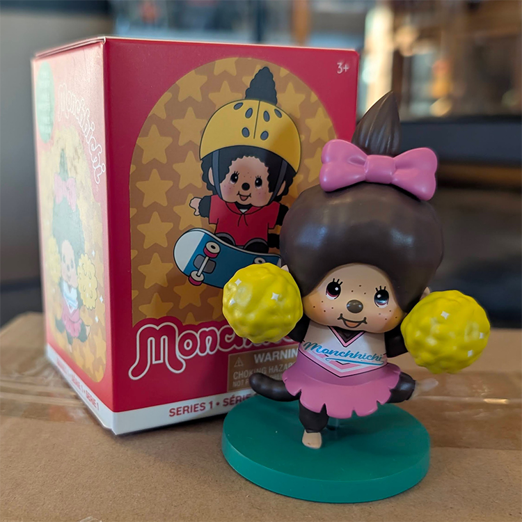 Sekiguchi vinyl figure of Girl Monchhichi Cheerleader in pink outfit with yellow pom-poms on green stand