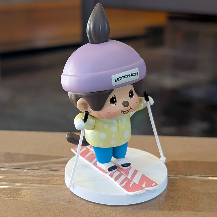 Sekiguchi Monchhichi Boy Skiing vinyl figure wearing purple helmet and yellow shirt on white snow-themed base