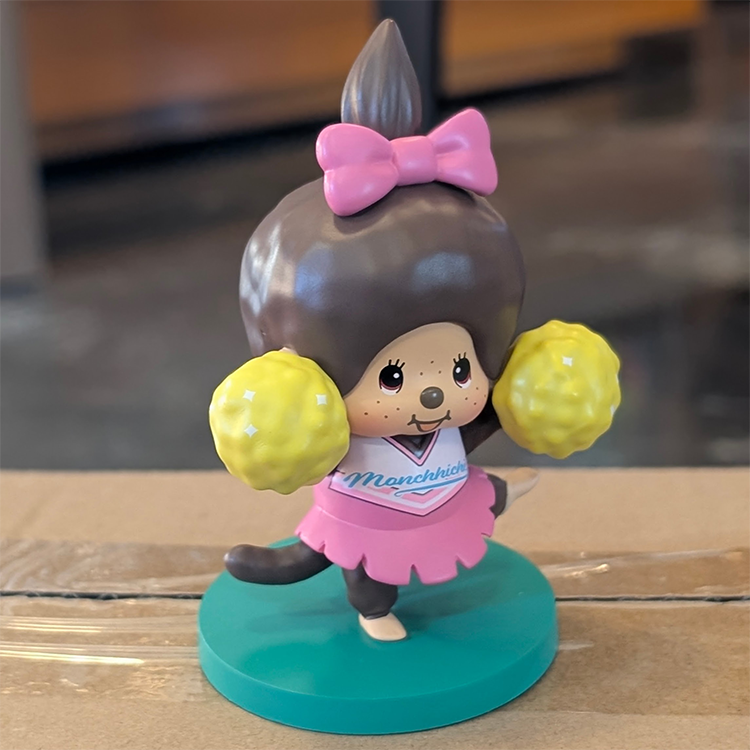 Sekiguchi Girl Monchhichi Cheerleader figure in pink uniform holding yellow pom-poms on green stand