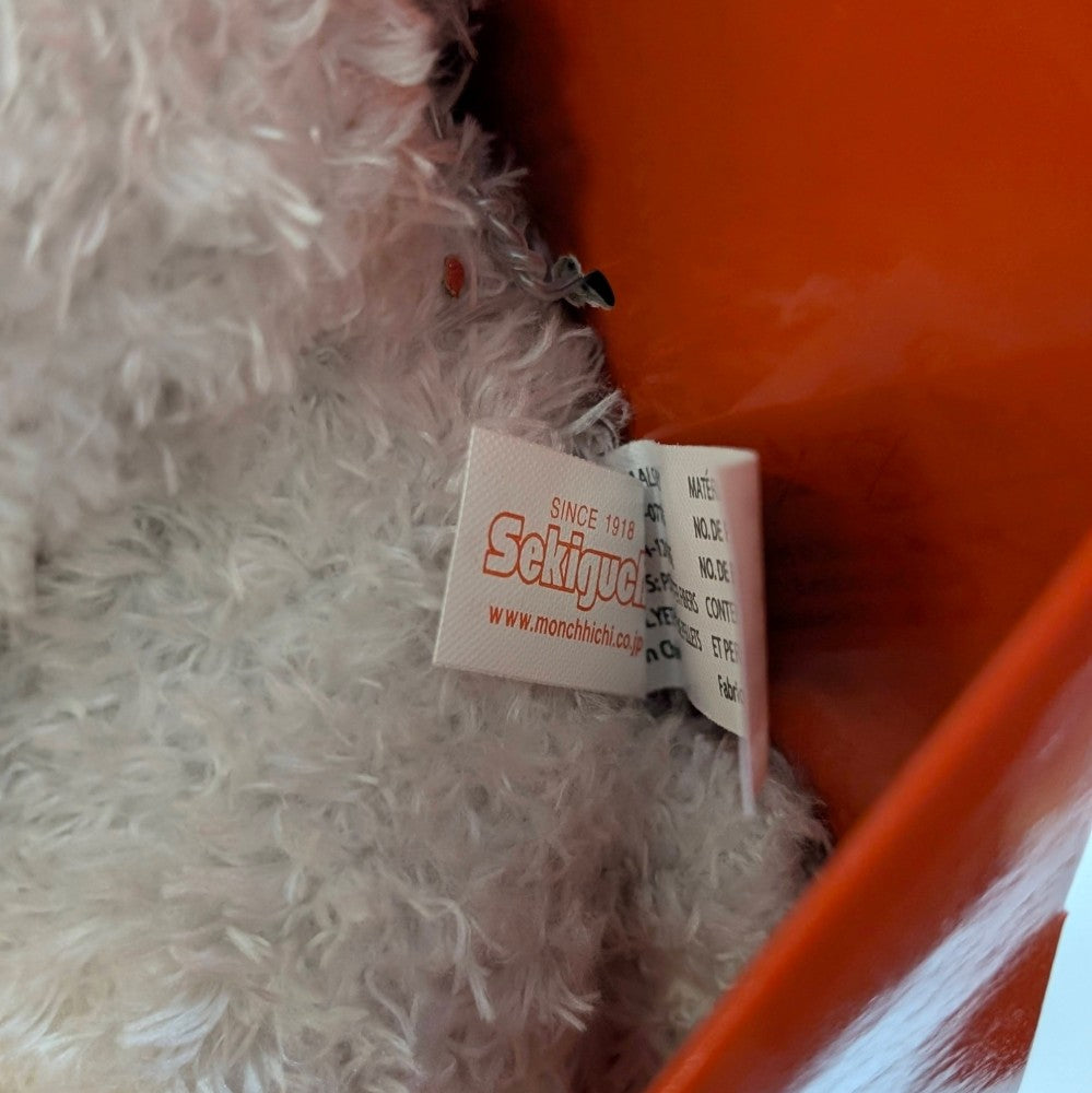 Close-up of Sekiguchi Monchhichi plush tag sewn into soft fluffy fabric showing brand details and care instructions