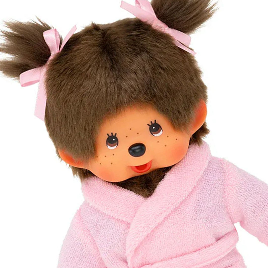 Sekiguchi Monchhichi girl plush with brown fur and pink bathrobe featuring twin ponytails and bow accents