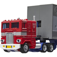 Red and blue vintage-style semi-truck toy replicating Hasbro's classic 1980s Optimus Prime figure with trailer.