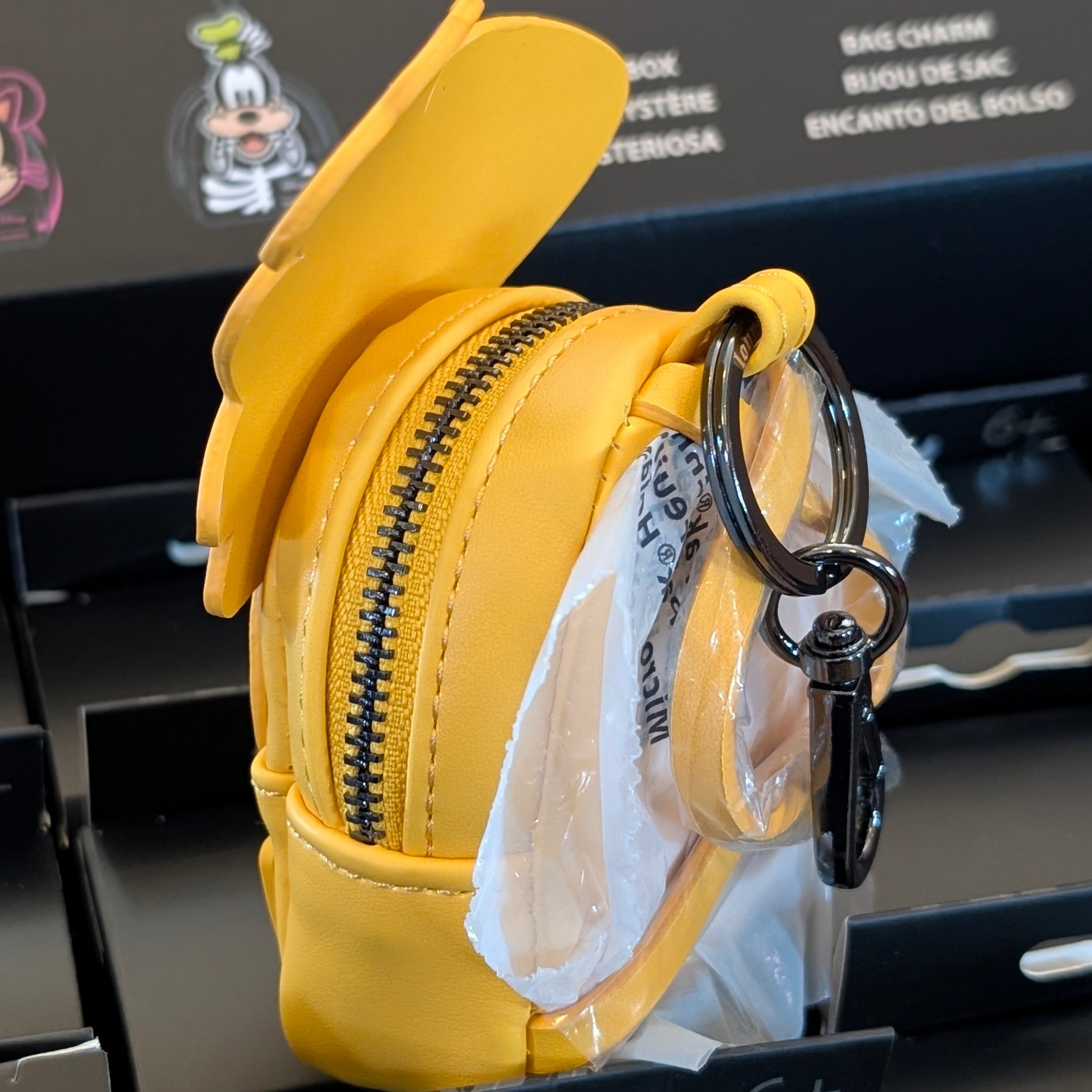 Yellow Loungefly mini backpack bag charm with black zipper and metal keyring attachment displayed in packaging