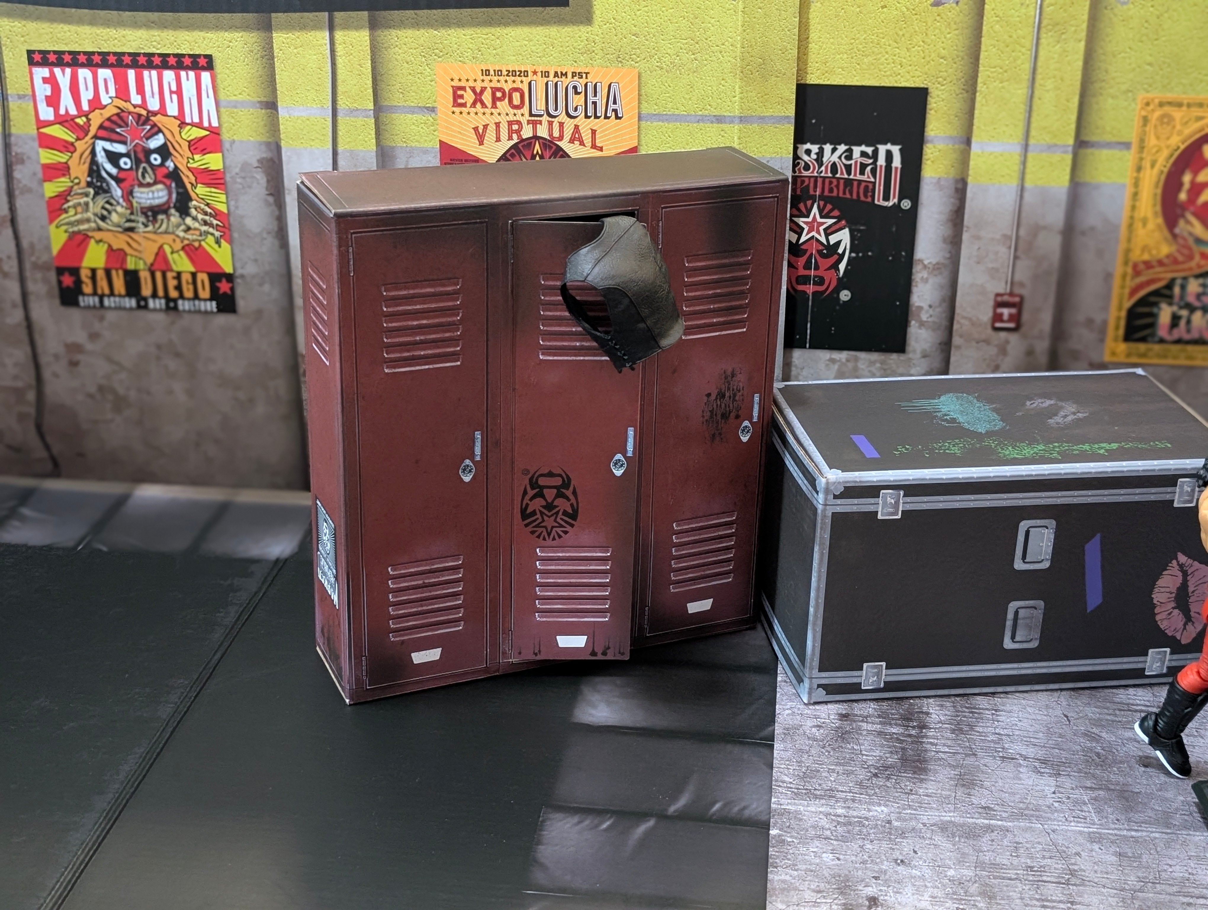 Red metal lockers with worn paint and stickers beside a black equipment case on a gym floor with posters on the wall
