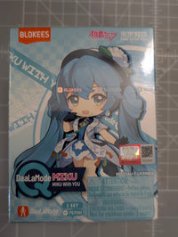 A Blokees DaalaLaMode MIKU Minju with You 1-set figure box photographed on a gray cutting mat background. The front of the box features a chibi-style anime character with long blue hair and a white-and-blue outfit, with Blokees branding and product details printed on the packaging.