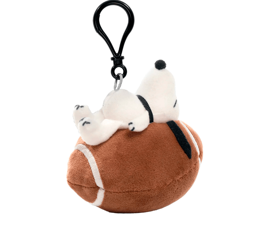 Go Figment Peanuts plush keychain featuring Snoopy lying on a football with a clip for bags or keys