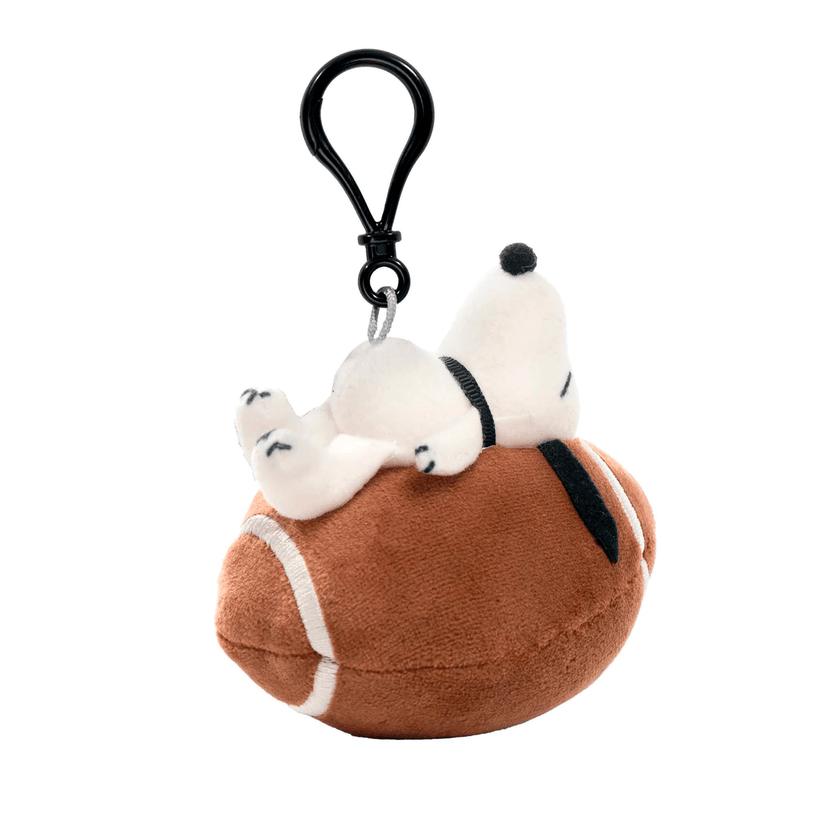 Go Figment Peanuts plush keychain featuring Snoopy lying on a football with a clip for bags or keys