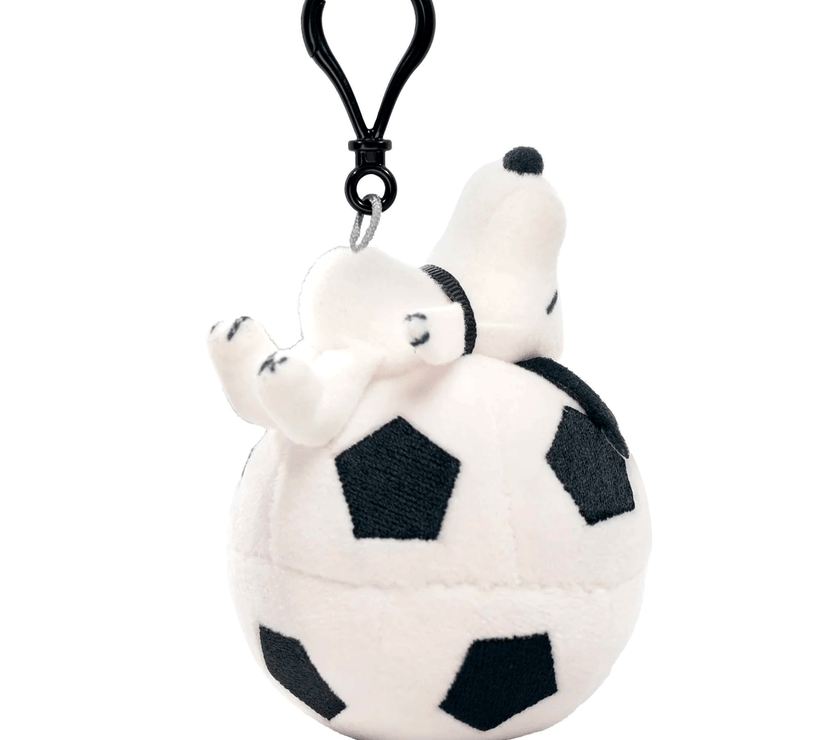 Go Figment plush Snoopy keychain lying on a soccer ball with a black clip attached above