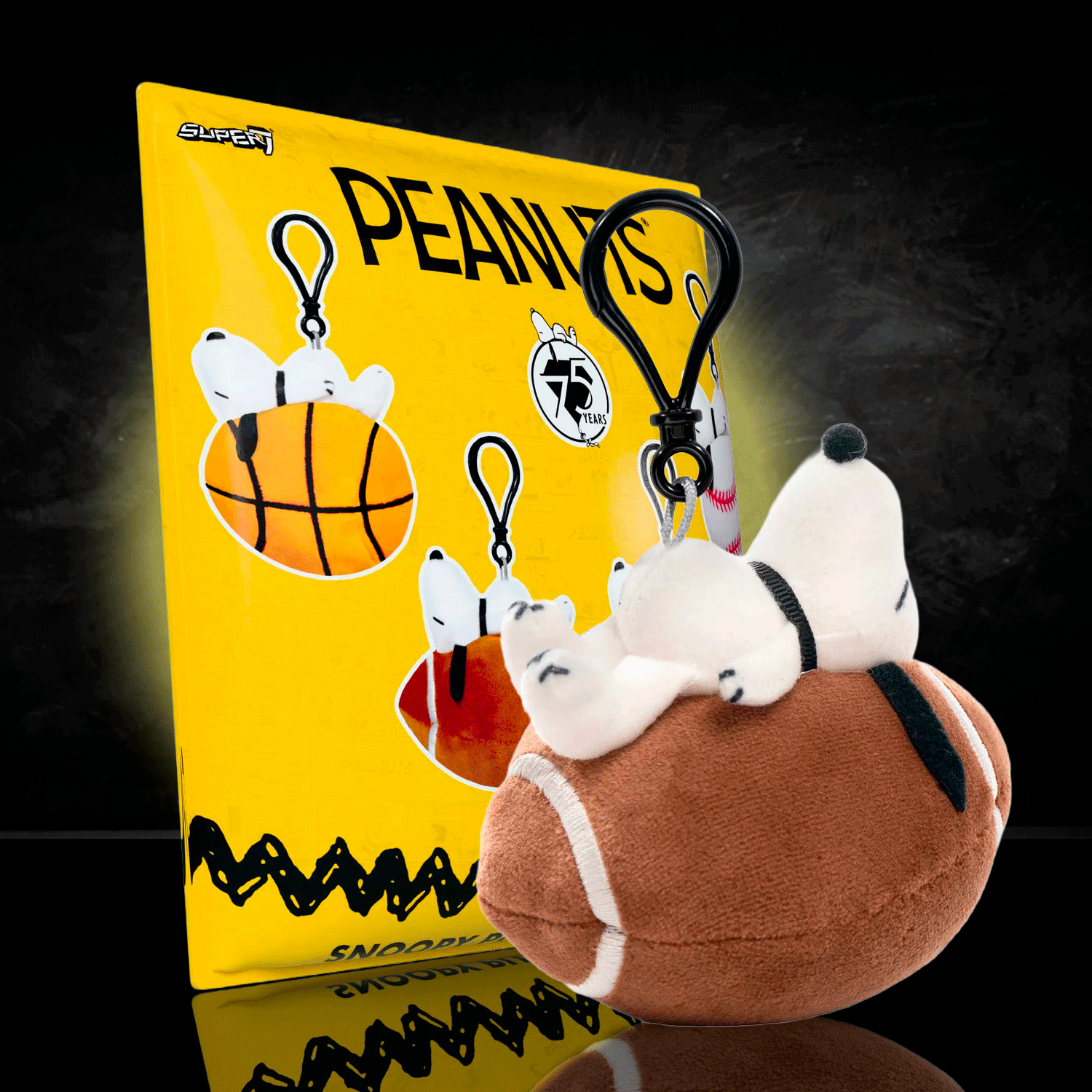 Go Figment Peanuts plush keychain featuring Snoopy lying on a football, sports-themed bag clip accessory.