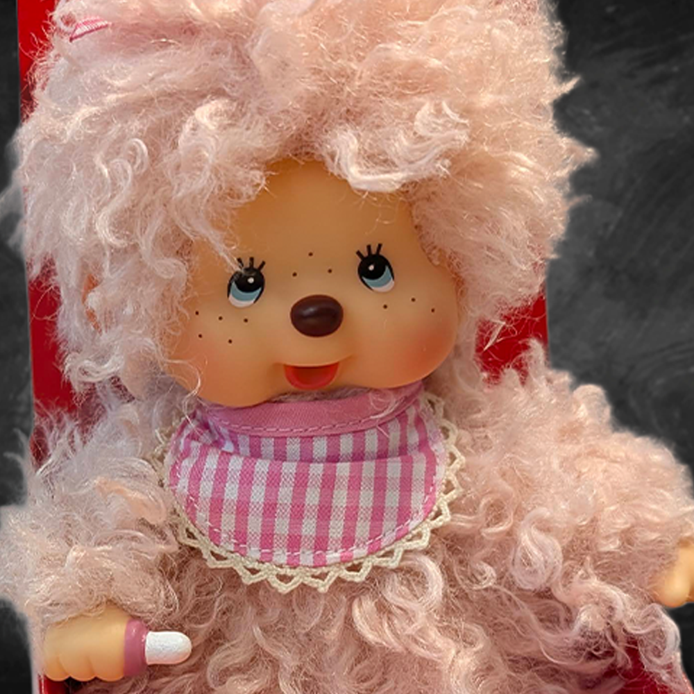 Sekiguchi Monchhichi 8-inch fluffy pink beige plush monkey with blue eyes and gingham bib close-up view