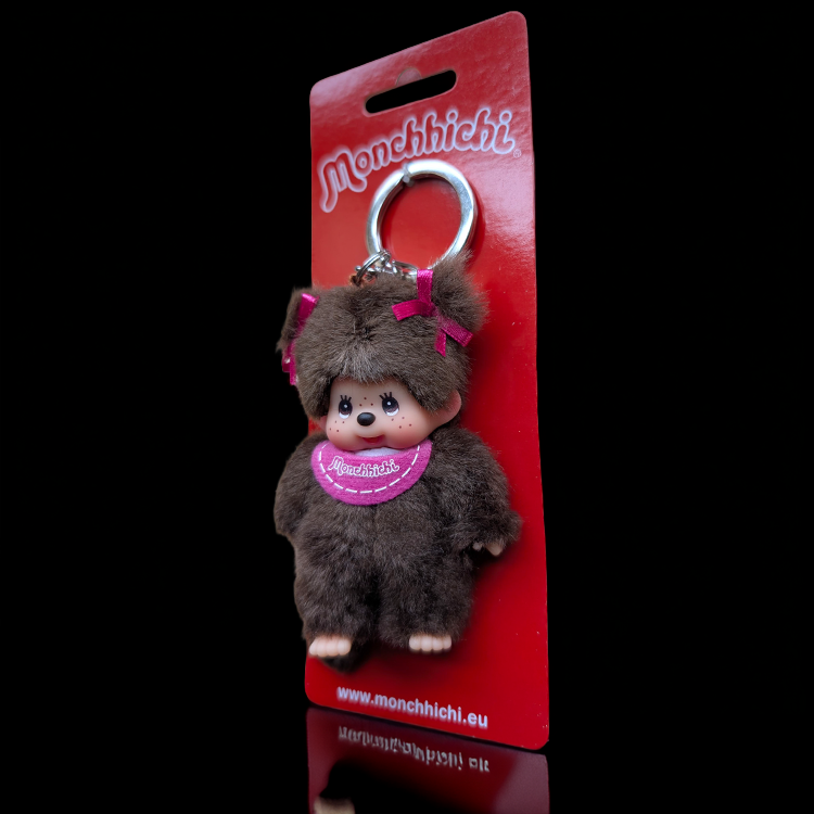 Sekiguchi Monchhichi classic girl plush keychain with pigtails and pink bib on red backing card.