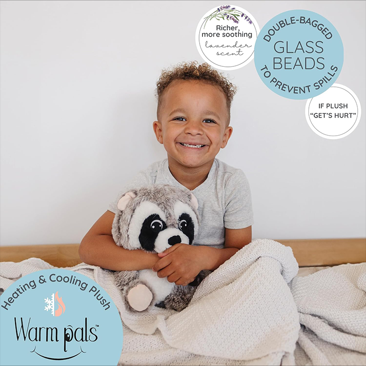 Child smiling and holding a microwavable lavender-scented raccoon plush toy for warmth and comfort
