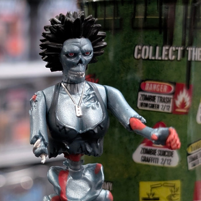 Super7 “Trash” metallic blue graffiti female zombie figure with spiked hair posed in front of green warning sign background