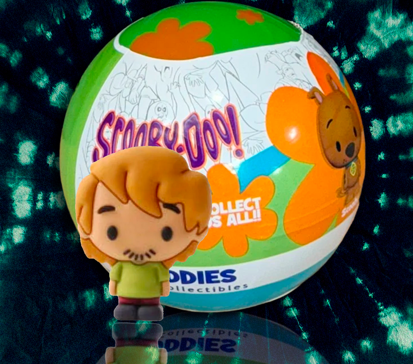 Scooby-Doo mini figure collectible by UCC with colorful mystery ball packaging in background on reflective surface