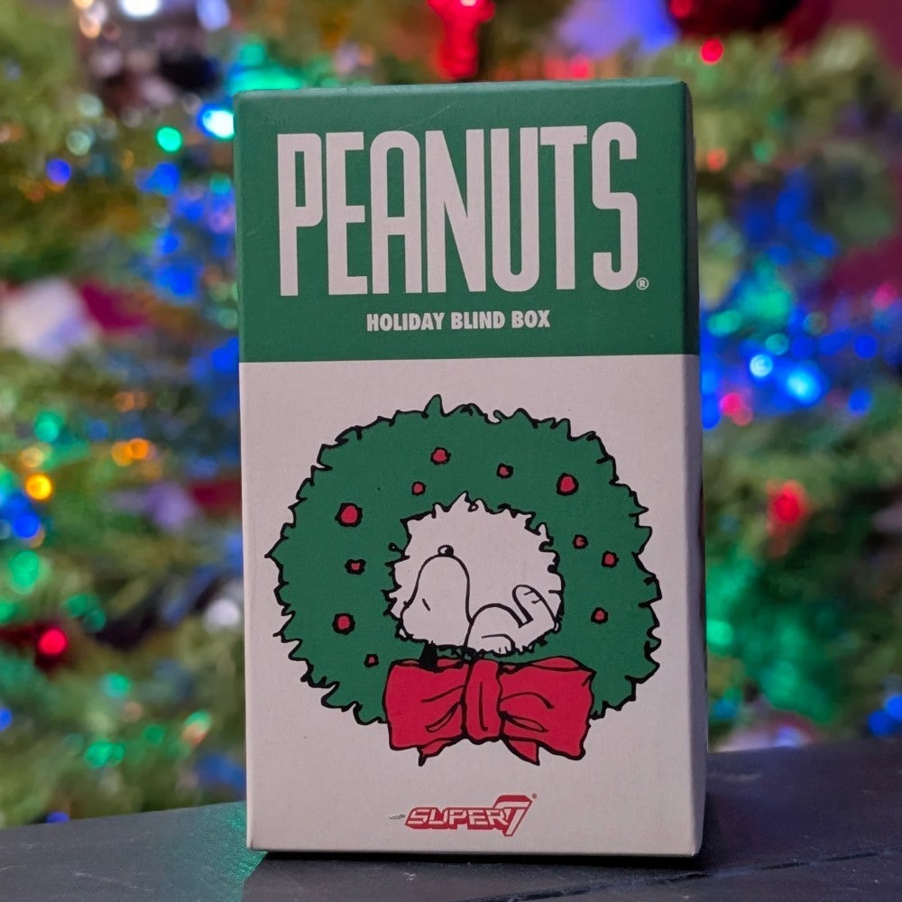 Super7 Peanuts Holiday Blind Box featuring Snoopy inside green wreath with red bow and colorful festive lights background