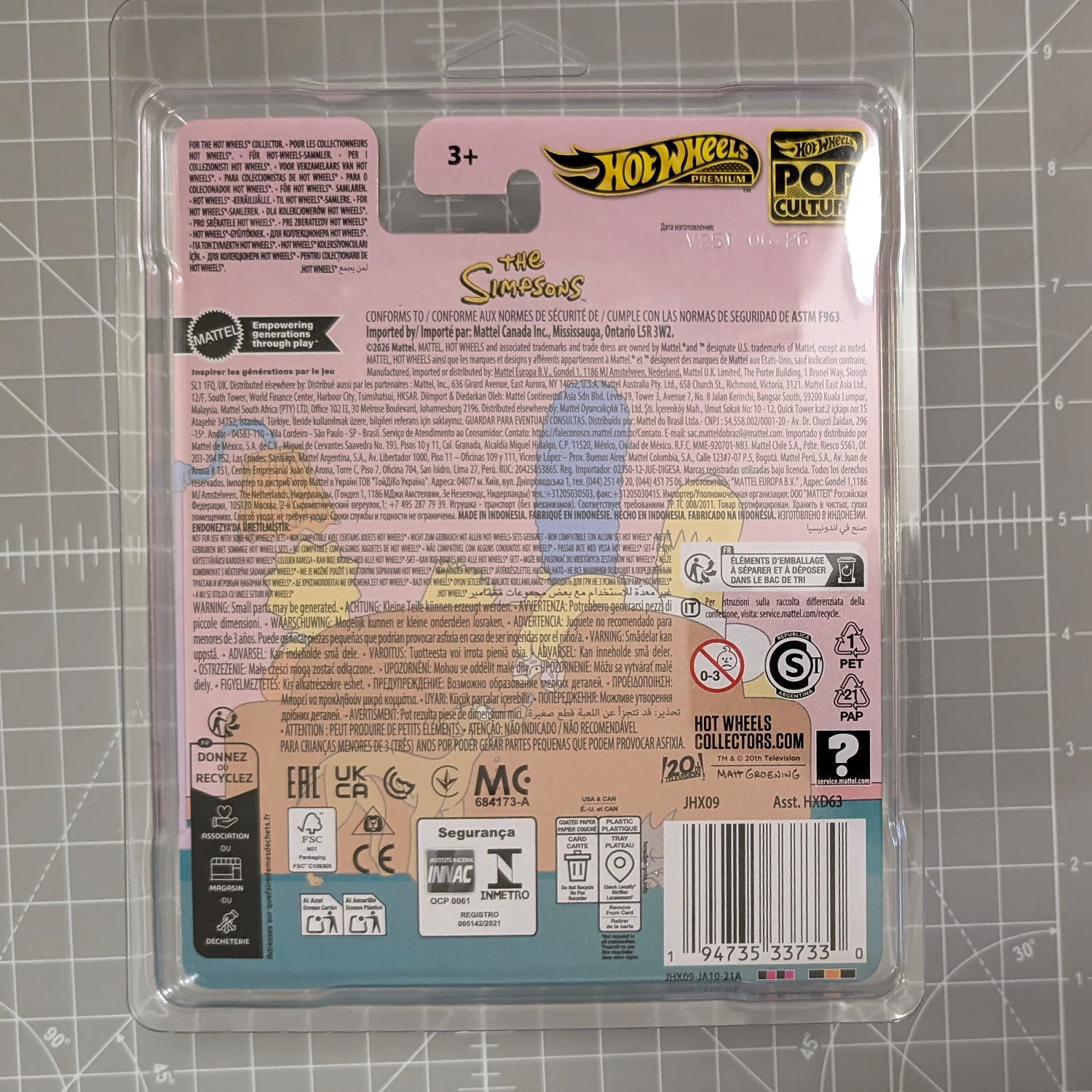 Back of Hot Wheels Pop Culture packaging featuring The Simpsons branding, safety symbols, recycling icons, and a barcode