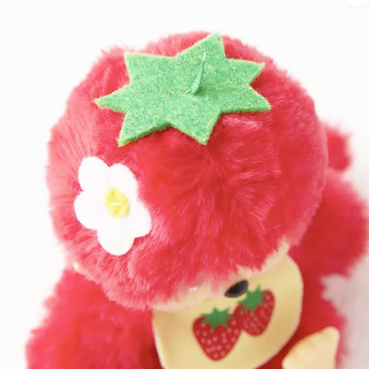 Close-up of Sekiguchi Monchhichi plush in bright red strawberry color with green leaf and white flower details.