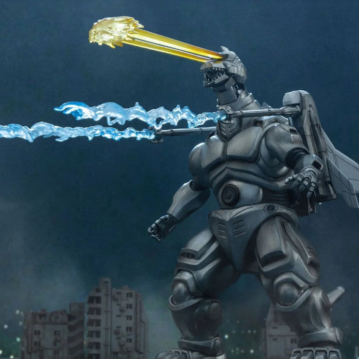 Godzilla stands in a cityscape at night, rendered as a metallic gray robot with a glowing blue sword and a golden beam weapon above its head. The image includes Godzilla logo text in the top right and small product text along the left edge.