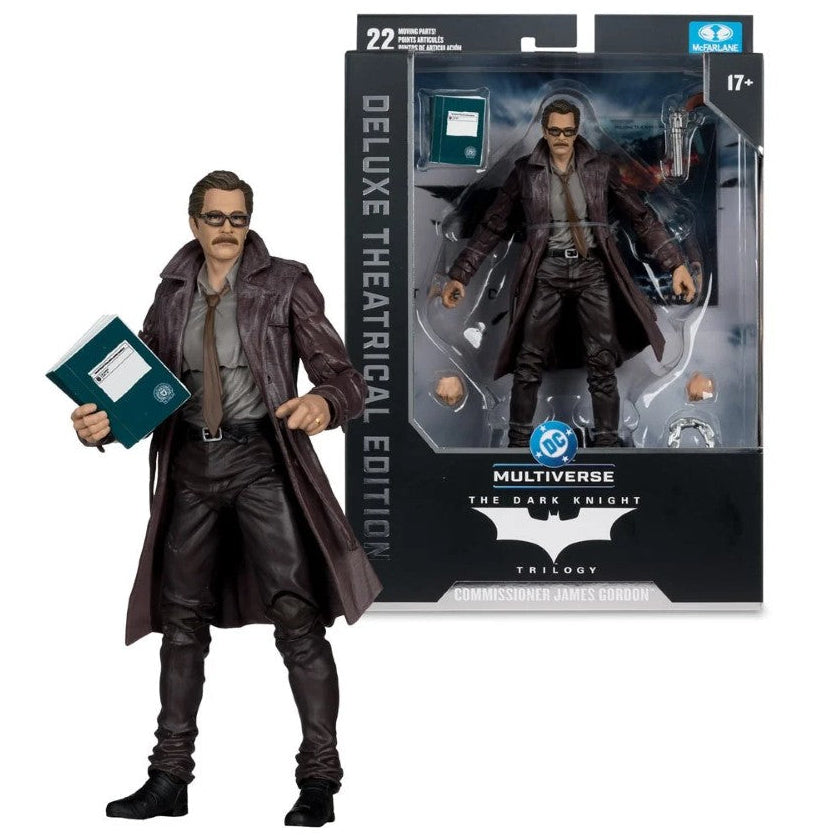 Multiverse The Dark Knight: Batman - The Dark Knight: Theatrical Edition action figure shown next to its retail packaging. The figure is dressed in a dark brown trench coat, gray shirt, and black pants, holding a teal book.