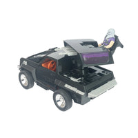 Black toy off road vehicle with an action figure, open rear compartment, rugged tires, and mounted equipment