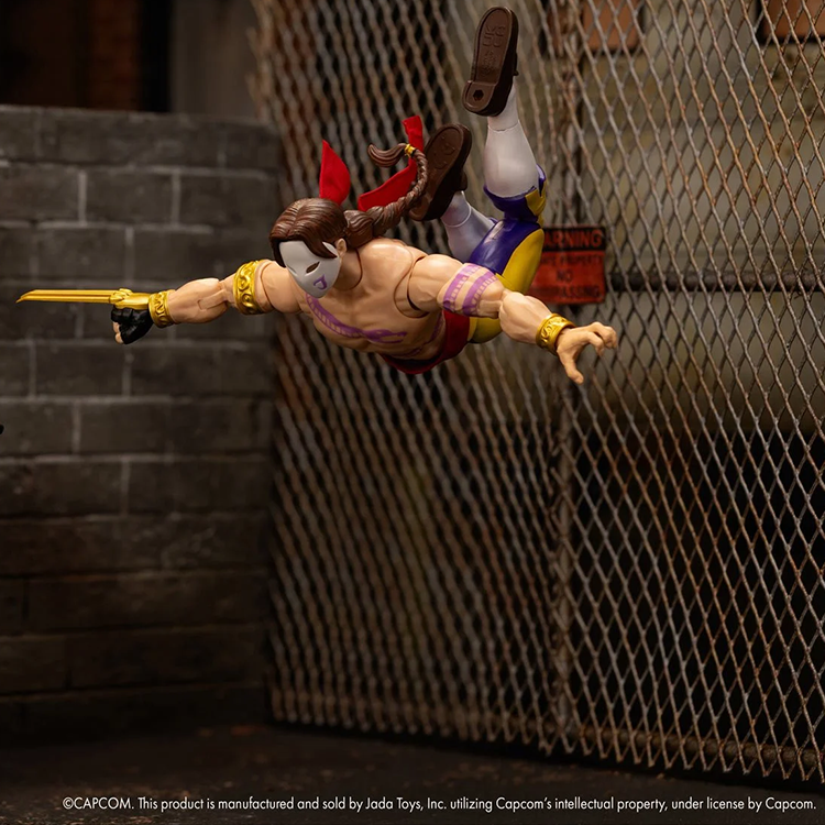 Jada Toys Ultra Street Fighter II Vega 6-inch action figure posed mid-air against chain-link fence background