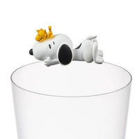 K-Wonderland Peanuts Snoopy cup figure lying on glass rim with Woodstock perched on Snoopy’s head in relaxed pose